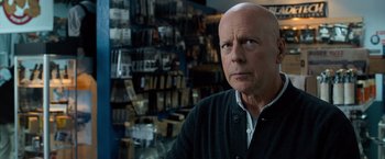 Movie still from “Death Wish” (2018), directed by Eli Roth – A bald man in a black jacket in front of a store; Close Up shot, Over the shoulder angle
