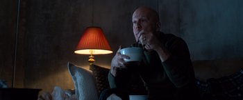 Movie still from “Death Wish” (2018), directed by Eli Roth – A man sitting on a couch eating a bowl of food; Medium shot, Low angle