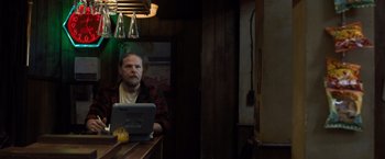 Movie still from “Death Wish” (2018), directed by Eli Roth – A man sitting in front of a laptop computer on top of a counter; Medium shot, Low angle