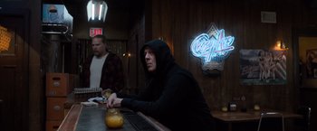 Movie still from “Death Wish” (2018), directed by Eli Roth – A man sitting at a table in front of a neon sign; Medium shot, Over the shoulder angle
