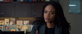 Movie still from “Death Wish” (2018), directed by Eli Roth – A woman with dreadlocks sitting in a room; Close Up shot, Over the shoulder angle