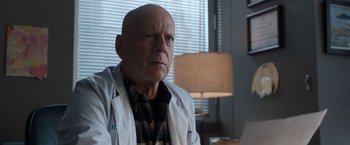 Movie still from “Death Wish” (2018), directed by Eli Roth – An older bald man wearing a white lab coat; Close Up shot, Low angle
