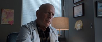 Movie still from “Death Wish” (2018), directed by Eli Roth – A man in a lab coat sitting in front of a lamp; Close Up shot, Low angle