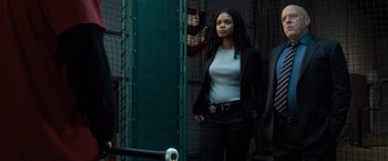 Movie still from “Death Wish” (2018), directed by Eli Roth – A woman standing next to a fence looking at the camera; Medium shot, Low angle