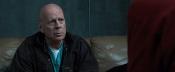 Movie still from “Death Wish” (2018), directed by Eli Roth – A man sitting on top of a couch in a living room; Close Up shot, Over the shoulder angle