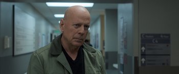 Movie still from “Death Wish” (2018), directed by Eli Roth – A bald man in a black shirt and a green jacket; Close Up shot, Over the shoulder angle