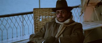 Movie still from “Death in Venice” (1971), directed by Luchino Visconti – A man wearing a hat and a scarf sitting in a chair; Close Up shot, Low angle
