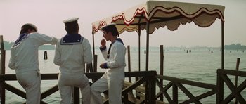 Movie still from “Death in Venice” (1971), directed by Luchino Visconti – Two men standing on a pier next to the ocean; Wide shot, Over the shoulder angle