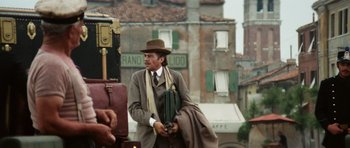 Movie still from “Death in Venice” (1971), directed by Luchino Visconti – A man in a suit and hat holding an umbrella; Medium shot, Low angle