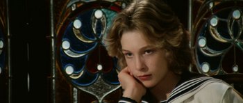 Movie still from “Death in Venice” (1971), directed by Luchino Visconti – A young woman sitting in front of a stained glass window; Close Up shot, High angle