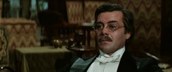 Movie still from “Death in Venice” (1971), directed by Luchino Visconti – A person wearing glasses and a bow tie; Close Up shot, Low angle