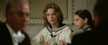 Movie still from “Death in Venice” (1971), directed by Luchino Visconti – A young woman sitting at a table with a glass of wine in front of her; Close Up shot, Over the shoulder angle