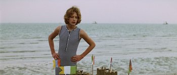 Movie still from “Death in Venice” (1971), directed by Luchino Visconti – A young man standing on the beach next to shells; Medium shot, Over the shoulder angle