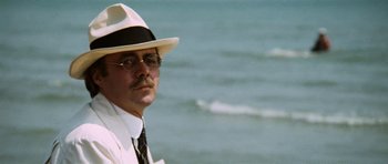 Movie still from “Death in Venice” (1971), directed by Luchino Visconti – A man in a white suit and a white hat standing in front of the ocean; Close Up shot, Low angle