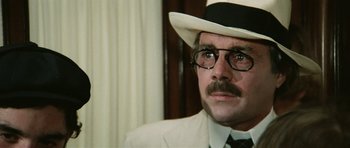 Movie still from “Death in Venice” (1971), directed by Luchino Visconti – A person wearing a hat and glasses; Close Up shot, Over the shoulder angle