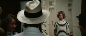 Movie still from “Death in Venice” (1971), directed by Luchino Visconti – A woman in a hat and a striped shirt looking in a mirror; Medium shot, Over the shoulder angle