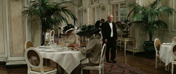 Movie still from “Death in Venice” (1971), directed by Luchino Visconti – A man and a woman in a formal dress sitting at a dinner table; Wide shot, Low angle