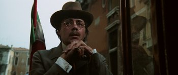 Movie still from “Death in Venice” (1971), directed by Luchino Visconti – A man in a hat and glasses looking out of a window; Close Up shot, Low angle