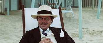 Movie still from “Death in Venice” (1971), directed by Luchino Visconti – A man in a suit and hat sitting in a chair; Close Up shot, Low angle