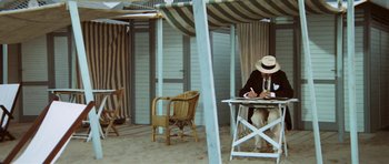 Movie still from “Death in Venice” (1971), directed by Luchino Visconti – A man sitting at a table writing on a piece of paper; Wide shot, High angle