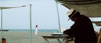 Movie still from “Death in Venice” (1971), directed by Luchino Visconti – A woman standing on a beach near a pier; Wide shot, Over the shoulder angle
