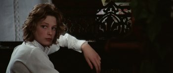 Movie still from “Death in Venice” (1971), directed by Luchino Visconti – A young girl sitting on a couch in a room; Close Up shot, Over the shoulder angle