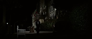 Movie still from “Death in Venice” (1971), directed by Luchino Visconti – A group of people standing in front of a large building at night; Wide shot, Over the shoulder angle
