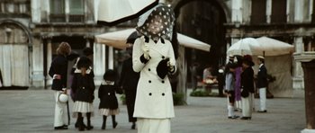 Movie still from “Death in Venice” (1971), directed by Luchino Visconti – A woman in a white coat holding an umbrella; Medium shot, Low angle