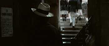 Movie still from “Death in Venice” (1971), directed by Luchino Visconti – A man wearing a hat sitting on some stairs; Close Up shot, Low angle