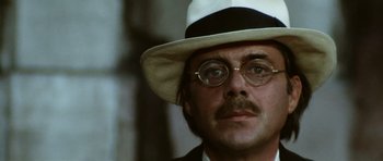 Movie still from “Death in Venice” (1971), directed by Luchino Visconti – A person wearing glasses and a hat; Close Up shot, Low angle
