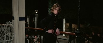 Movie still from “Death in Venice” (1971), directed by Luchino Visconti – A woman in a black suit standing next to a railing; Medium shot, Low angle