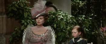 Movie still from “Death in Venice” (1971), directed by Luchino Visconti – A woman in a dress and a hat with feathers on her head; Close Up shot, Over the shoulder angle
