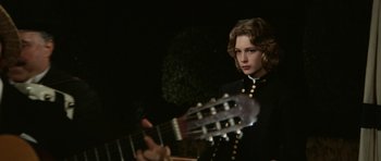 Movie still from “Death in Venice” (1971), directed by Luchino Visconti – A young woman holding a guitar in front of a black background; Medium shot, Over the shoulder angle