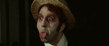 Movie still from “Death in Venice” (1971), directed by Luchino Visconti – A person wearing a hat and sticking out his tongue; Close Up shot, Low angle