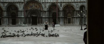 Movie still from “Death in Venice” (1971), directed by Luchino Visconti – Two people are standing in front of a flock of pigeons; Extreme Wide shot, High angle