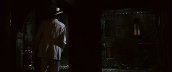 Movie still from “Death in Venice” (1971), directed by Luchino Visconti – A man wearing a hat standing in the dark; Wide shot, Over the shoulder angle