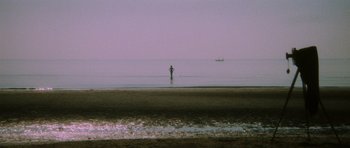 Movie still from “Death in Venice” (1971), directed by Luchino Visconti – A person standing in the water on a beach; Extreme Wide shot, High angle
