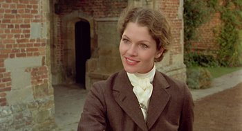 Movie still from “Death on the Nile” (1978), directed by John Guillermin – A woman wearing a suit and tie smiling for the camera; Close Up shot, Over the shoulder angle