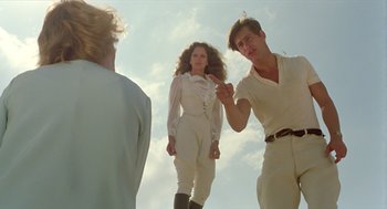 Movie still from “Death on the Nile” (1978), directed by John Guillermin – A man and a woman standing next to each other in front of another man; Medium shot, Low angle