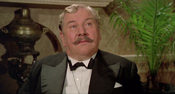 Movie still from “Death on the Nile” (1978), directed by John Guillermin – A person wearing a suit and tie; Close Up shot, Low angle