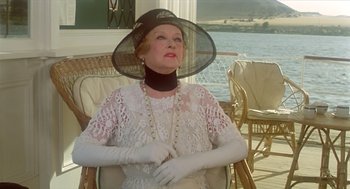 Movie still from “Death on the Nile” (1978), directed by John Guillermin – An older woman wearing a hat and white gloves; Medium shot, Low angle