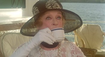Movie still from “Death on the Nile” (1978), directed by John Guillermin – An older woman drinking a cup of coffee; Close Up shot, High angle