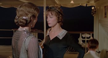 Movie still from “Death on the Nile” (1978), directed by John Guillermin – Two women are standing next to each other in front of an awning; Medium shot, Over the shoulder angle