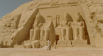 Movie still from “Death on the Nile” (1978), directed by John Guillermin – Two men walking in front of a large statue of ramesses the great; Extreme Wide shot, Low angle