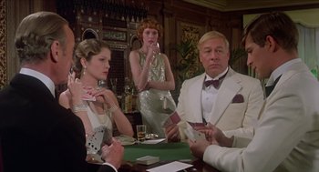 Movie still from “Death on the Nile” (1978), directed by John Guillermin – A group of people sitting at a table playing cards; Medium shot, Over the shoulder angle