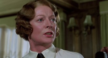 Movie still from “Death on the Nile” (1978), directed by John Guillermin – An older woman in a white shirt and black tie; Close Up shot, Low angle