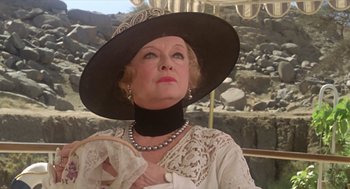 Movie still from “Death on the Nile” (1978), directed by John Guillermin – An older woman wearing a black hat and a white dress; Close Up shot, Low angle