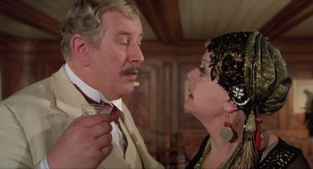 Movie still from “Death on the Nile” (1978), directed by John Guillermin – An older man wearing a suit and tie and a woman wearing a black dress; Close Up shot, Over the shoulder angle