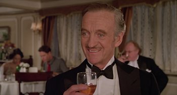 Movie still from “Death on the Nile” (1978), directed by John Guillermin – An older man in a tuxedo holding a glass of wine; Close Up shot, Low angle