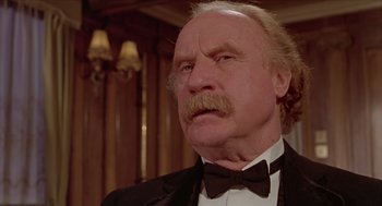 Movie still from “Death on the Nile” (1978), directed by John Guillermin – An older man in a suit and bow tie; Close Up shot, Low angle